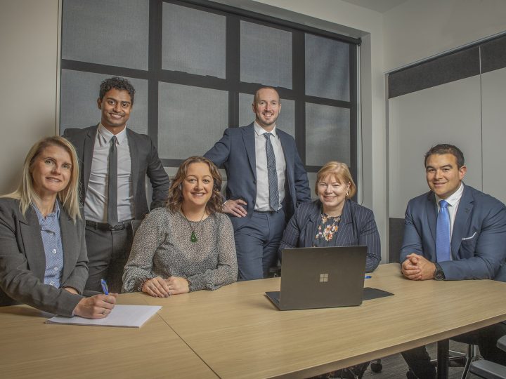 Corcoran French law firm team photo showing our people & legal exprtise. Legal experts sitting at desk with window in back ground.